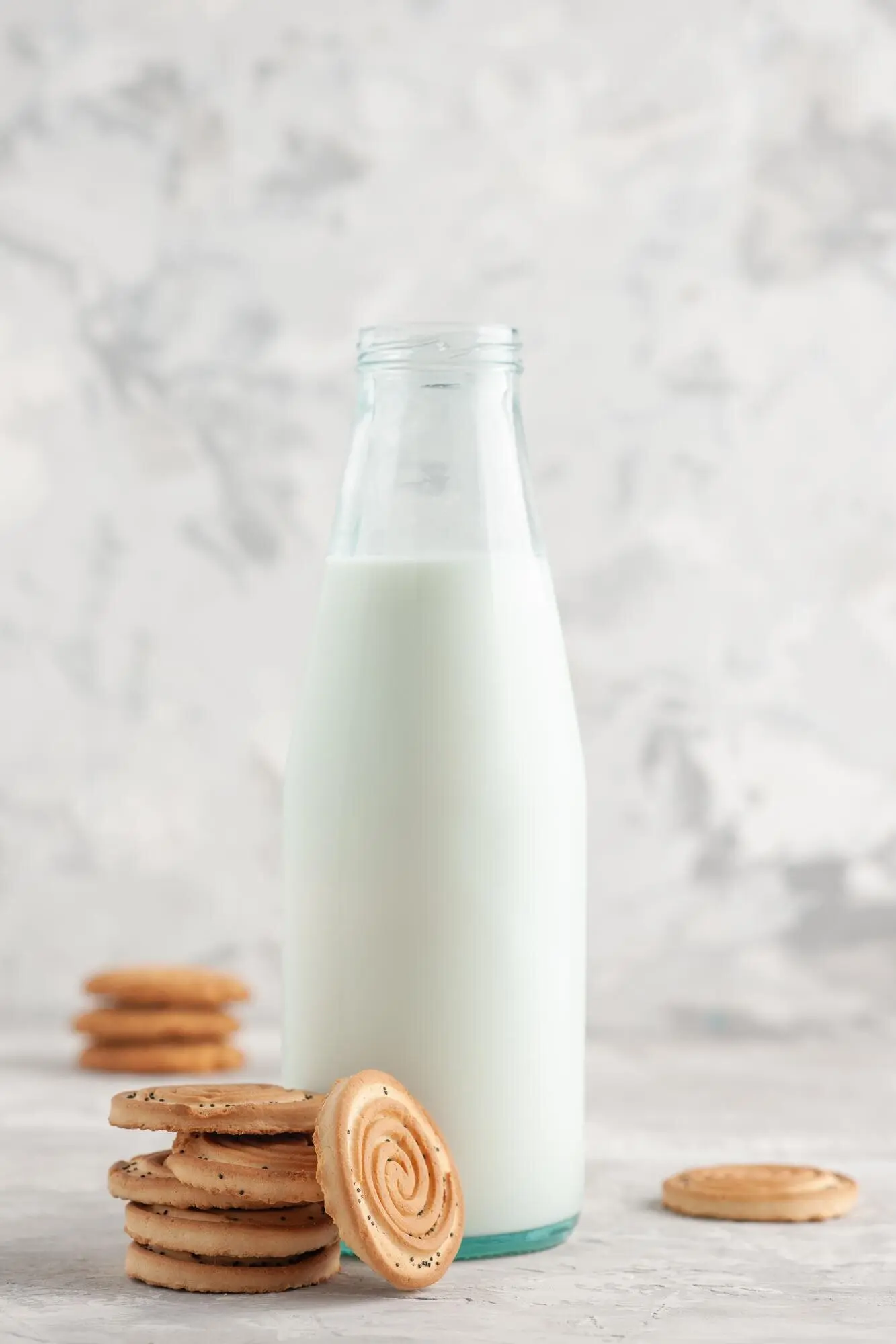 여백이 있는 얼룩진 흰 배경에서 정면으로 본, 우유와 쿠키로 채워진 열린 유리병.